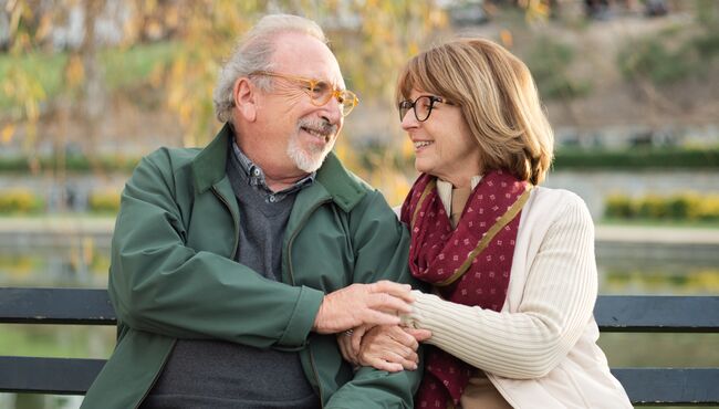 Couple talks on a bench with arms linked